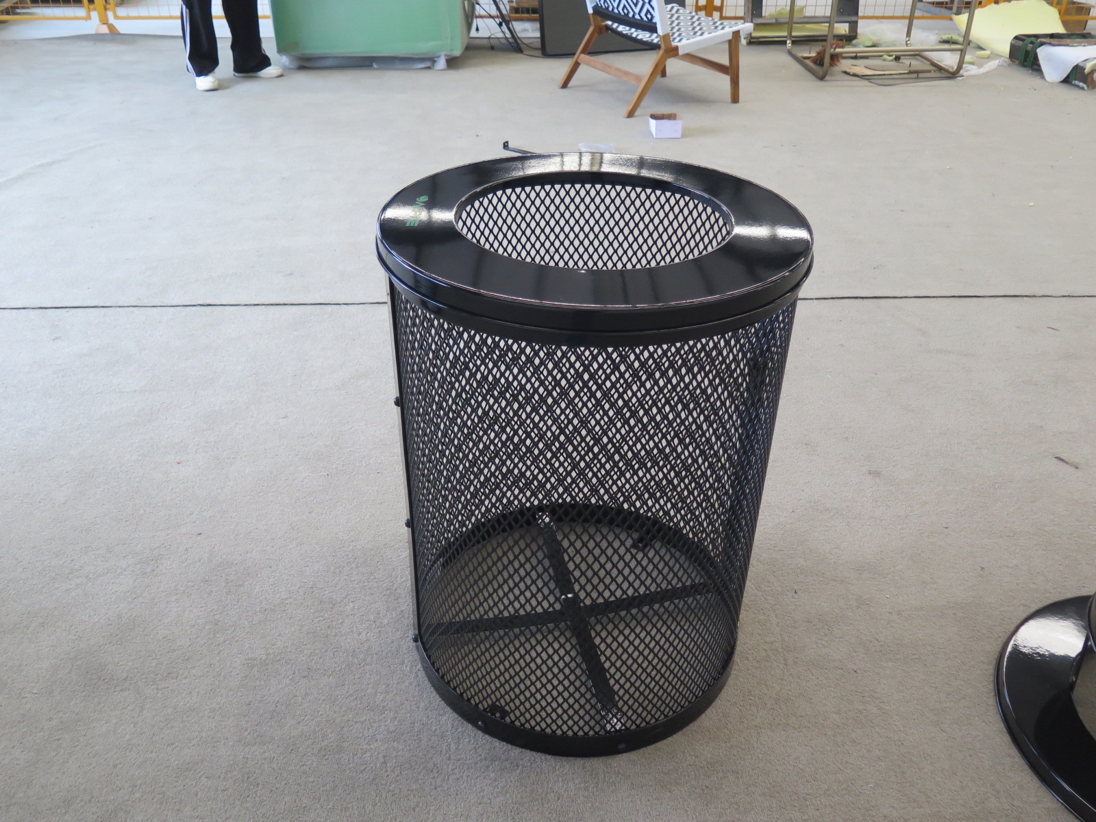 Heavy-duty powder-coated wire mesh outdoor trash can with reinforced metal rim.